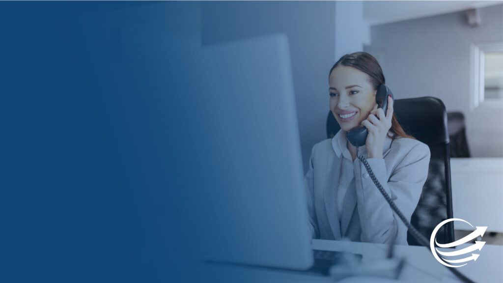 Woman sits at computer desk using Nored Telcom's office phone systems
