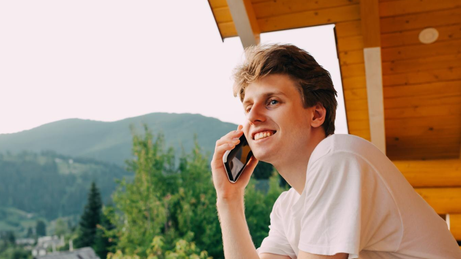 Man on a porch with a mountain backdrop, talking on the phone, portraying the freedom cloud phones in Knoxville offer for employees to work anywhere.