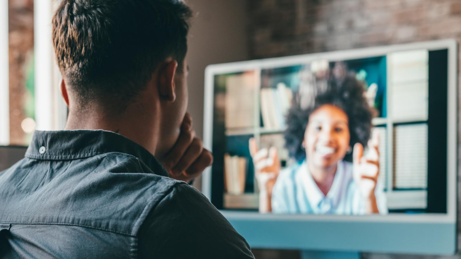 Man in a video call with a smiling colleague, emphasizing collaboration and remote management enabled by cloud communications and (sometimes) artificial intelligence.