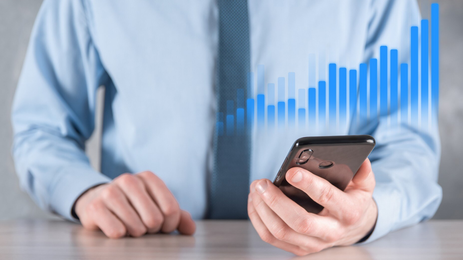 Close-up of a businessman holding a smartphone with a digital bar chart, illustrating cloud services that scale with your organization and strategy.