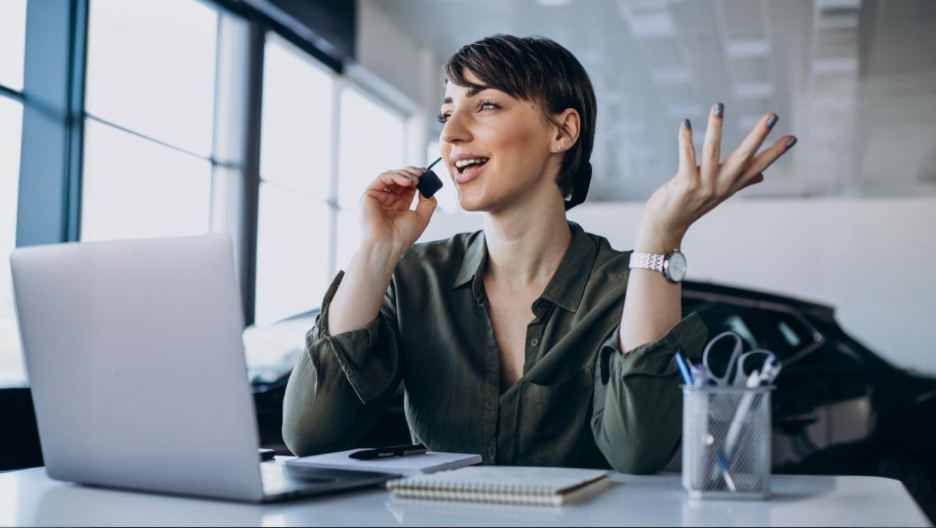 Smiling woman using a headset while speaking to a client at her laptop, showcasing the benefits of business phone systems.